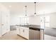 Open-concept kitchen with white cabinets, black countertops, island with sink, and stainless steel dishwasher at 9264 Biscay St, Commerce City, CO 80022