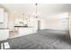 Open living space featuring carpet, a center kitchen island, white cabinets, and modern lighting at 9264 Biscay St, Commerce City, CO 80022