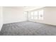 Spacious living room with neutral walls, gray carpet, and plenty of natural light from large windows at 9264 Biscay St, Commerce City, CO 80022