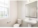 Clean half bathroom featuring a pedestal sink, toilet, and a window providing natural light at 9264 Biscay St, Commerce City, CO 80022