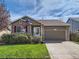 Brick ranch home with attached garage, landscaping, and American flag at 11462 Iola St, Commerce City, CO 80640
