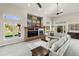 Bright living room featuring a brick fireplace, modern furnishings, and large windows overlooking the landscaped backyard at 5925 Zinnia Ct, Arvada, CO 80004
