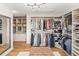 Beautiful walk-in closet with custom shelves, hardwood floors, ottoman, and mirror at 5925 Zinnia Ct, Arvada, CO 80004