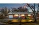 Charming red brick single story home featuring a attached garage, green front lawn, and mature trees at dusk at 6359 Brooks Dr, Arvada, CO 80004