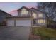 Charming two-story home with a well-manicured lawn and a three-car garage at dusk at 6470 S Oak Ct, Littleton, CO 80127