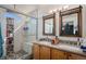 Stylish bathroom featuring a glass enclosed shower with stone accents and a double vanity with framed mirrors at 19681 E 59Th Pl, Aurora, CO 80019