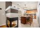 Well-lit kitchen features an island with seating, granite countertops, wood cabinetry, and a cozy fireplace in adjacent living space at 19681 E 59Th Pl, Aurora, CO 80019