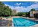 A refreshing community pool surrounded by lounging chairs and lush greenery under a bright, cloudy sky at 3465 S Poplar St # 506, Denver, CO 80224