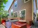 Back exterior view of a home with brown siding, a red patio, table, chairs and a tree at 1288 S Beeler Ct, Denver, CO 80247