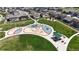 Aerial view of a colorful neighborhood playground with various play structures and picnic areas, surrounded by green space at 13488 Wabash St, Thornton, CO 80602