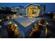 Backyard with gas firepit, barbeque area, and landscaping, beautifully illuminated at night at 1925 Peregrine Dr, Brighton, CO 80601