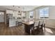 Bright kitchen with white cabinets, marble countertops, stainless steel appliances, and a dark-wood dining table at 1925 Peregrine Dr, Brighton, CO 80601