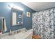 Stylish bathroom with a marble countertop vanity, a decorative mirror, and a blue and white shower curtain at 6994 W Hinsdale Dr, Littleton, CO 80128