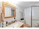 Bright bathroom with a wood-framed mirror, neutral counter, and glass-enclosed shower at 6994 W Hinsdale Dr, Littleton, CO 80128