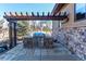 Built-in stainless steel outdoor grill with stone base and wood pergola, set on a stone patio by the home at 4691 Bandera Pl, Parker, CO 80134