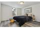Bedroom with a black quilt, accent pillows, modern mirror, window, gray wood-look flooring and wicker side table at 1498 S Perry St, Denver, CO 80219