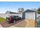 Spacious garage with a car parked in front, set in a gravel driveway and surrounded by fencing for privacy at 1498 S Perry St, Denver, CO 80219