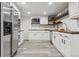 Bright kitchen with stainless appliances, white cabinetry, wood countertops, wood shelving, and gray wood-look floors at 1498 S Perry St, Denver, CO 80219