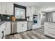 Updated kitchen with white cabinets, stainless steel appliances, black subway tile backsplash, and durable gray hardwood flooring at 1498 S Perry St, Denver, CO 80219