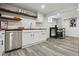 White kitchen with wood countertops, floating shelves, stainless dishwasher, table, chairs and gray wood-look floors at 1498 S Perry St, Denver, CO 80219