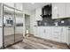Modern kitchen featuring stainless steel appliances, white cabinets, granite countertops, and stylish gray hardwood floors at 1498 S Perry St, Denver, CO 80219