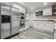 Kitchen with stainless appliances, white cabinets, wood countertops, gray wood-look floors and door to room at 1498 S Perry St, Denver, CO 80219