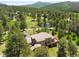 Stunning aerial view of the house, surrounded by trees with long driveway and outdoor decks at 7197 Timbers Dr, Evergreen, CO 80439