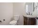 Elegant half-bath with a granite countertop, dark wood cabinet, and a decorative oval mirror at 7197 Timbers Dr, Evergreen, CO 80439