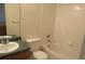 Bright bathroom featuring a shower-tub combo, neutral tile walls, and a vanity with a decorative countertop at 2517 S Genoa St, Aurora, CO 80013