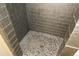 Modern shower stall featuring dark tile and pebble flooring at 2517 S Genoa St, Aurora, CO 80013