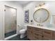 Modern bathroom featuring a glass shower, wooden vanity, round mirror, and decorative lighting at 3636 Sublime Ct, Castle Rock, CO 80108