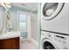 Bright bathroom features a shower-tub combo, stackable washer-dryer, and charming white and wood accents at 3333 W Hayward Pl, Denver, CO 80211