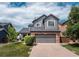Charming two-story home featuring gray siding, brick accents, a well-manicured lawn, and an attached two-car garage at 9758 Red Oakes Dr, Highlands Ranch, CO 80126