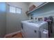 Functional laundry room with modern washer and dryer, shelving, and a window for natural light at 9758 Red Oakes Dr, Highlands Ranch, CO 80126