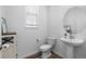 Bright powder room with pedestal sink, round mirror, modern toilet and wood-look flooring at 1168 Elbridge Dr, Elizabeth, CO 80107