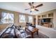 Comfortable living room with a ceiling fan, built-in shelving, and ample natural light from large windows at 40900 Red Fox Cir, Elizabeth, CO 80107
