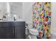 Modern bathroom featuring a dark vanity with sleek fixtures, a contemporary toilet, and a vibrant patterned shower curtain at 7077 Copper Sky Cir, Castle Pines, CO 80108