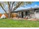 View of the green backyard featuring mature tree, string lights, patio, and comfortable seating at 3103 W Bellewood Dr, Englewood, CO 80110