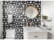 Bathroom boasts unique geometric patterned tile, gold fixtures, round mirror and white vanity at 3103 W Bellewood Dr, Englewood, CO 80110