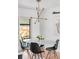 Modern dining area with stylish light fixture, white table, and sliding glass doors to the backyard at 3103 W Bellewood Dr, Englewood, CO 80110