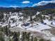 Expansive aerial view showcases home nestled among rolling, snow-dusted hills and towering trees at 20101 Spring Gulch Rd, Morrison, CO 80465