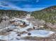 Panoramic aerial view of a home nestled amongst snow-covered terrain and mature trees, with a frozen pond at 20101 Spring Gulch Rd, Morrison, CO 80465