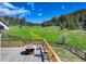 Deck with chairs and a table overlooking a lush green field and treelined mountains at 20101 Spring Gulch Rd, Morrison, CO 80465