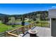 Deck overlooking lush green landscape with a pond and forested mountain view at 20101 Spring Gulch Rd, Morrison, CO 80465