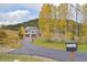 Two story home with an attached three car garage sits on a grassy lot with trees and a paved driveway at 20101 Spring Gulch Rd, Morrison, CO 80465