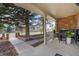 Spacious covered front porch with brick accents, seating area, and mature trees at 6302 S Ivy Ct, Centennial, CO 80111