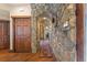 Stone hallway with wood floors and doors creating a rustic, yet elegant, interior design at 142 Outpost Ln, Evergreen, CO 80439