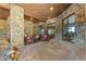 Covered stone patio with fireplace, stylish seating, and seamless indoor-outdoor transition through sliding glass doors at 142 Outpost Ln, Evergreen, CO 80439