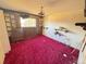 Dated bedroom featuring red carpet, wood-paneled walls, and a window view to the exterior at 7345 E Hinsdale Pl, Centennial, CO 80112