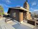 Angled view of the home featuring a stone chimney and wood siding at 7345 E Hinsdale Pl, Centennial, CO 80112